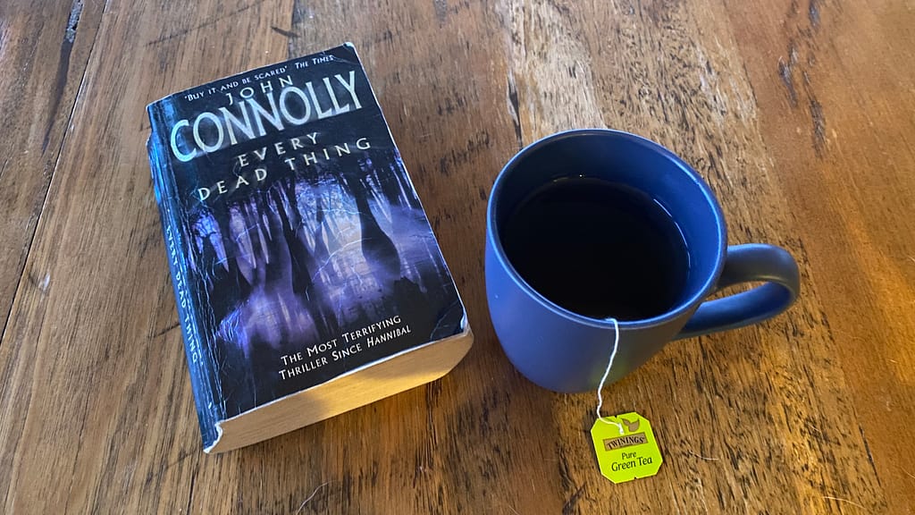 The book Every Dead Thing, but John Connolly sits on a timber table next to a cup of green tea.