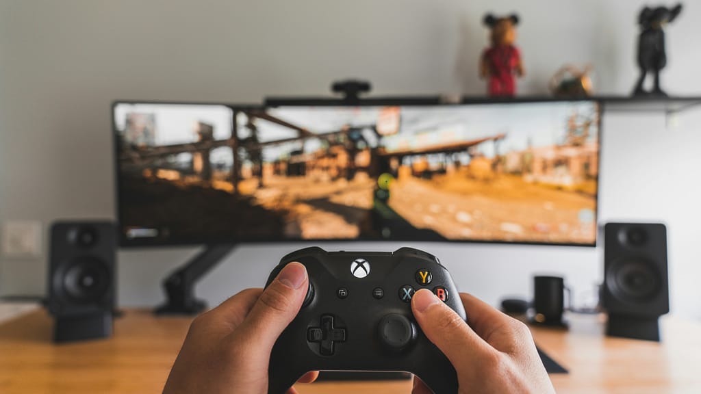 A gamer holds a controller in front of a computer screen.