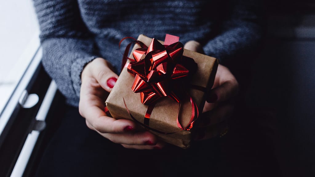 A woman holds a nicely wrapped gift. The inherited beliefs midlife women carry often don't feel like a gift.