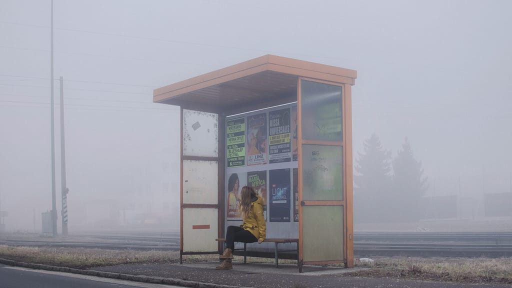 woman sits at bus stop.