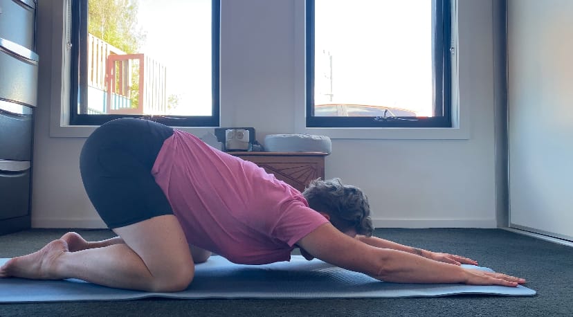 Em in puppy pose - stretching through her shoulders and chest.
