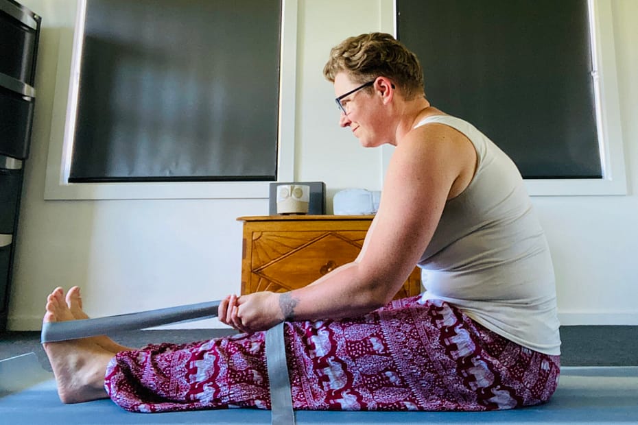 Em sits on the floor and uses a strap to pull herself towards her toes. She's in a 90-degree position. It's laughable.