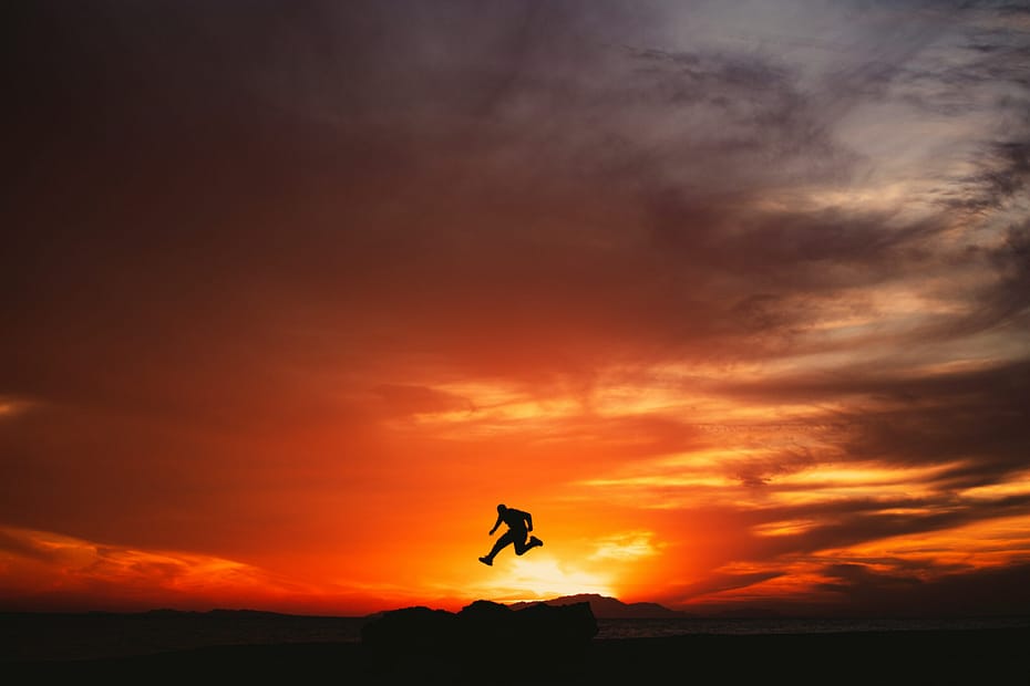 A person jumping into the air at sunset.