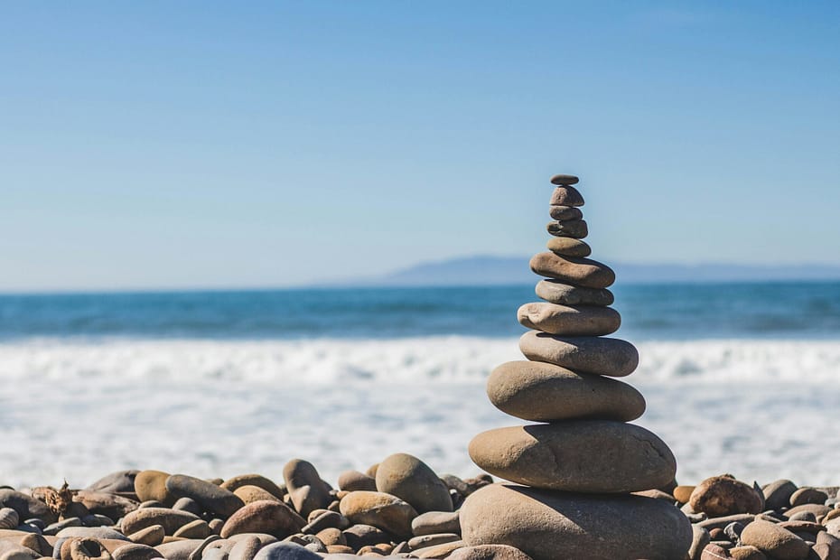 Rocks and pebbles stacked high (and carefully) on a rocky beach. The ocean is in the background.