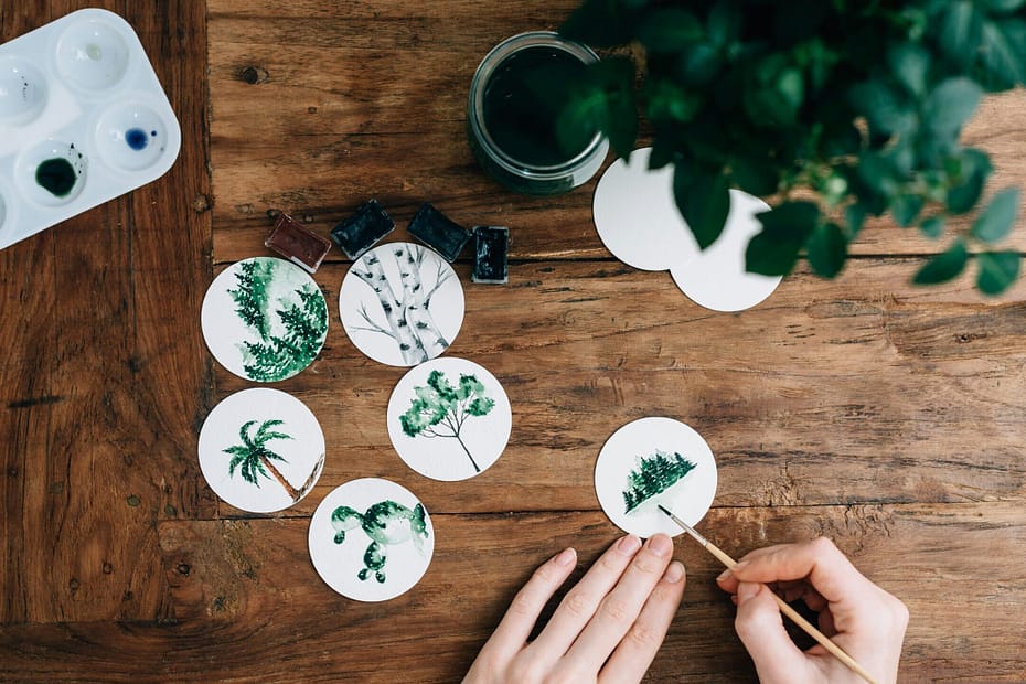 A woman does small watercolour paintings on small paper discs.