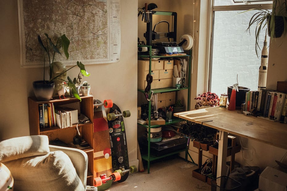 Bright and inviting home office with plants, books, a wall map, and two skateboards. The open window and personal touches show how thoughtful design supports space and mental health.