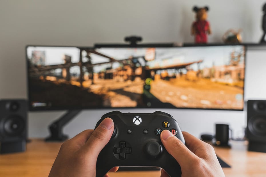 A gamer holds a controller in front of a computer screen.