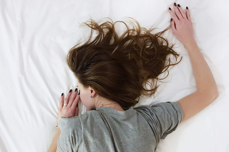 A woman sleeps on a white sheet.