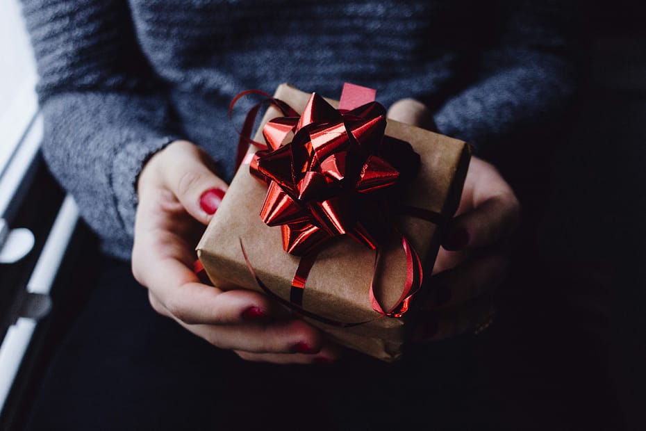 A woman holds a nicely wrapped gift. The inherited beliefs midlife women carry often don't feel like a gift.