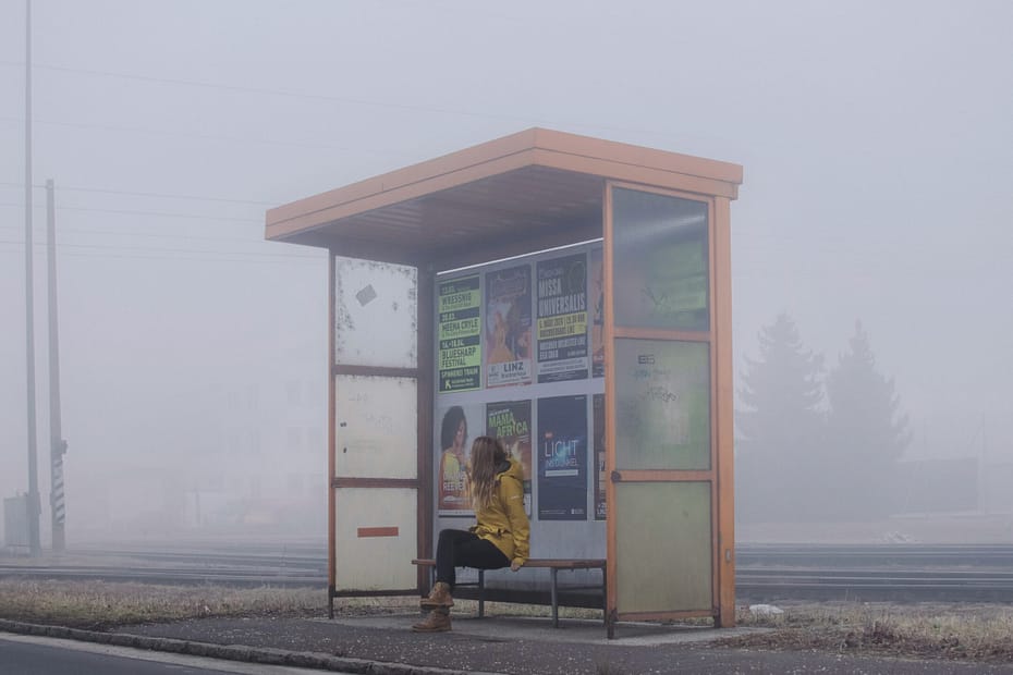 woman sits at bus stop.